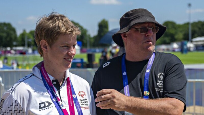 Young man and older man with awards around their necks. 